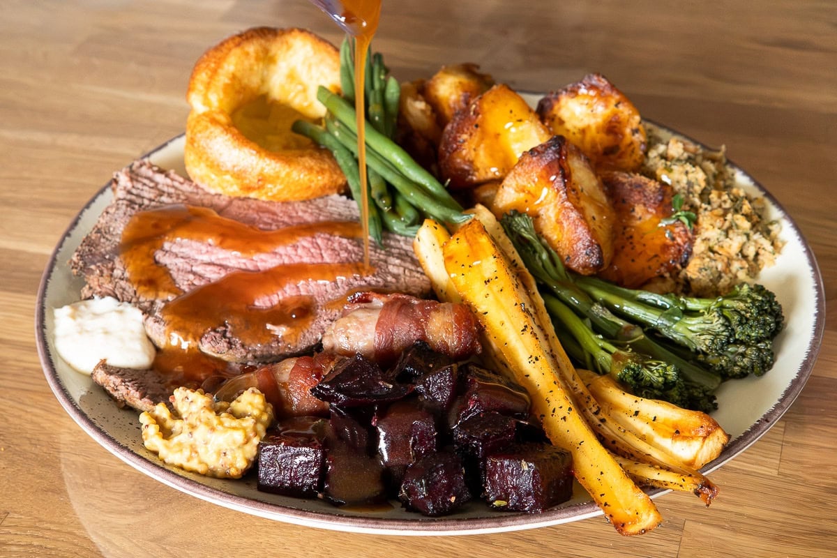 Succulent roasted beef with carrots, greens, potatoes and beetroot on a plated meal.