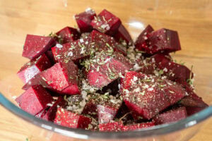 Beetroot cubes seasoned with herbs in glass bowl.