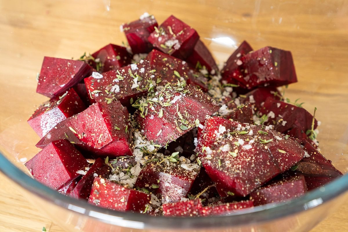 Beetroot cubes seasoned with herbs in glass bowl.